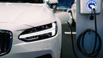 White hybrid vehicle charging at EV station showing plug-in hybrid technology