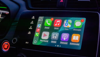 Modern vehicle dashboard displaying Apple CarPlay interface with smartphone apps including phone, music, maps, messages, and podcasts in Honda car interior